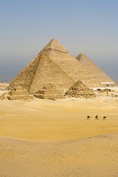 Pyramides de Gizeh avec des chameaux sur le sable sous un ciel bleu clair.